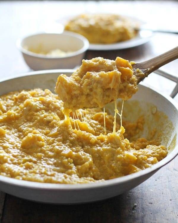 Squash curry quinoa in a skillet and on a wooden spoon.