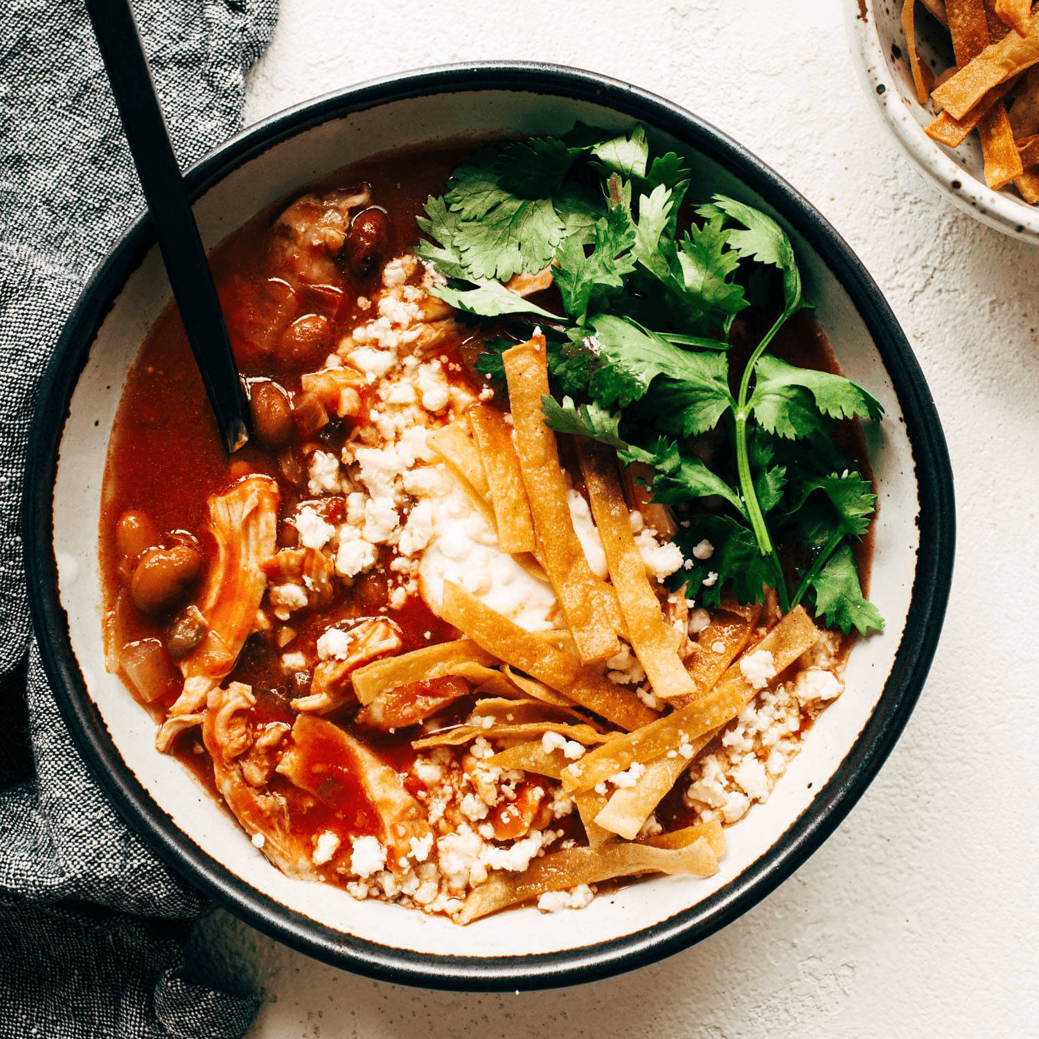 Chicken tortilla soup in a bowl with tortilla strips and cilantro.