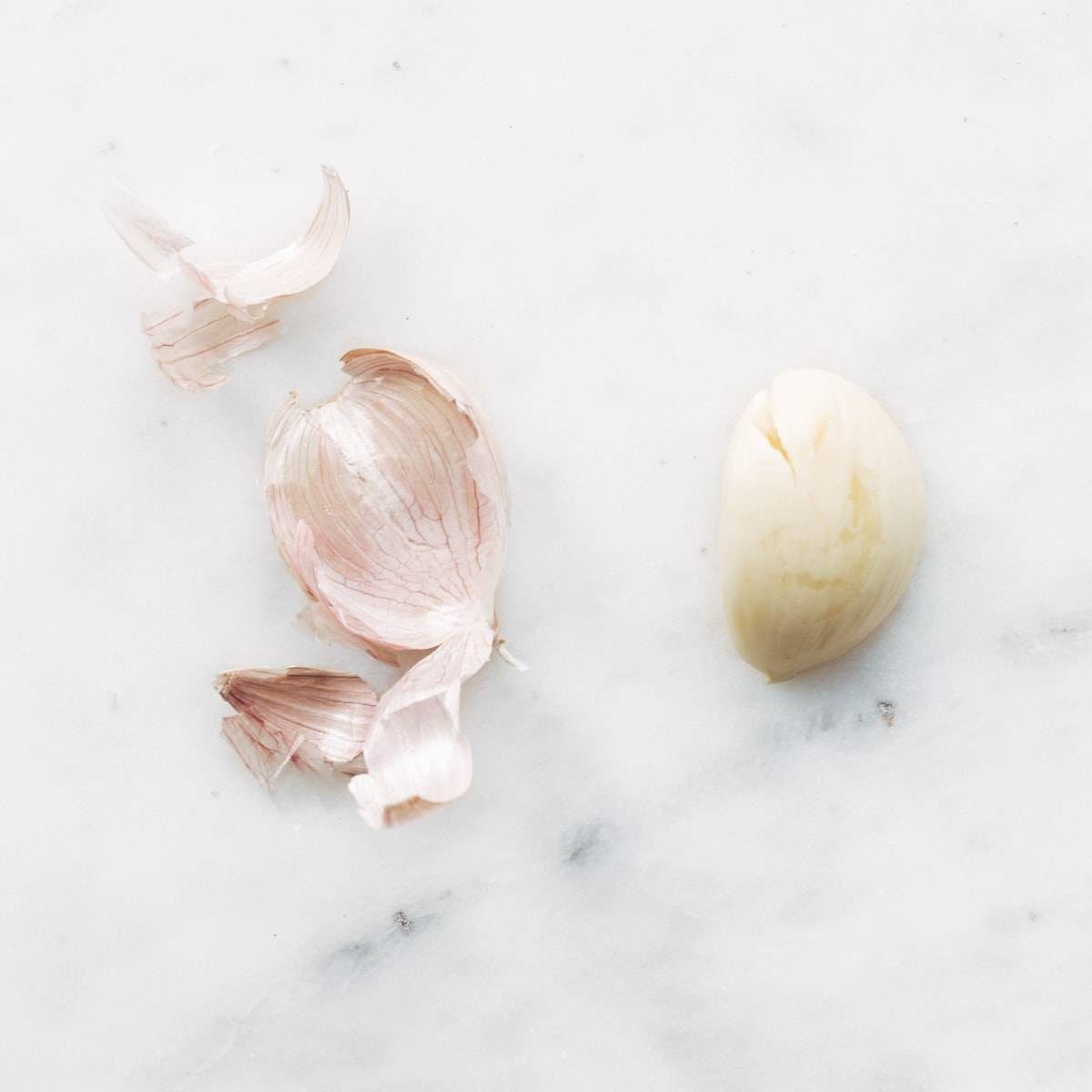 Garlic sitting on a white marbled surface.