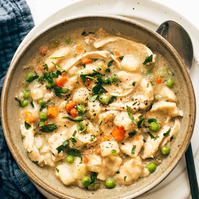 A bowl of chicken and dumplings with veggies in it.