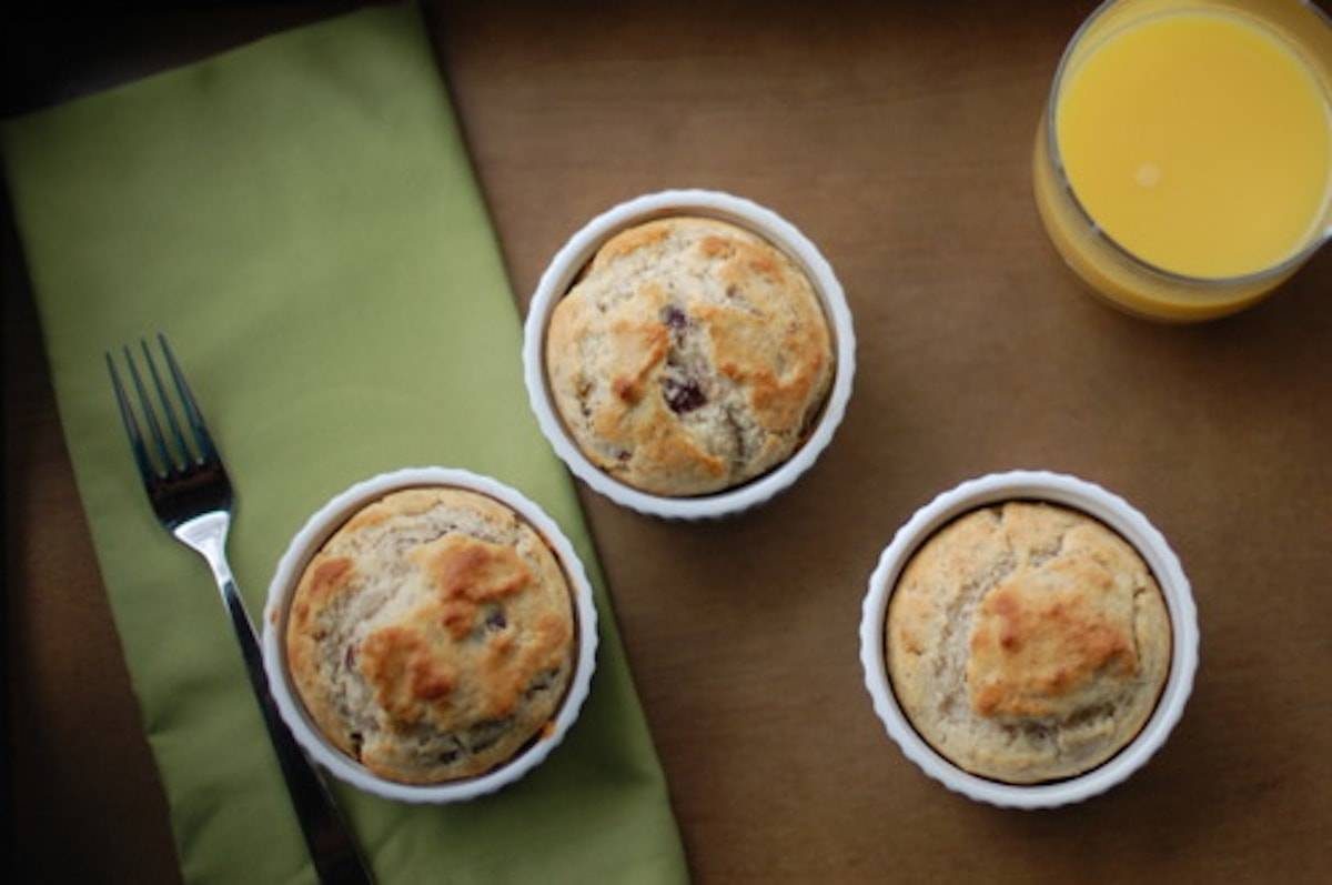 Three dishes of strawberry breakfast cakes in white dishes on a green napkin with a fork and orange juice.