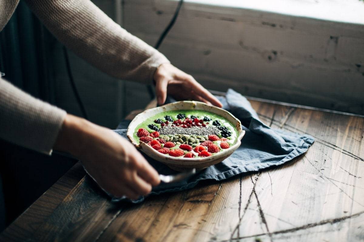Woman holding a bowl of fruit with a napkin.